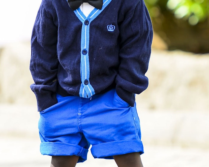 A smiling young child dressed up in a cardigan